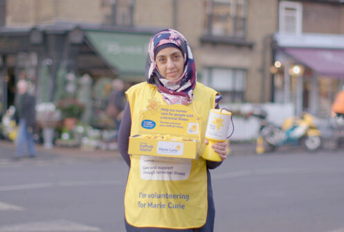 A fundraiser wearing a yellow overall from Marie Curie
