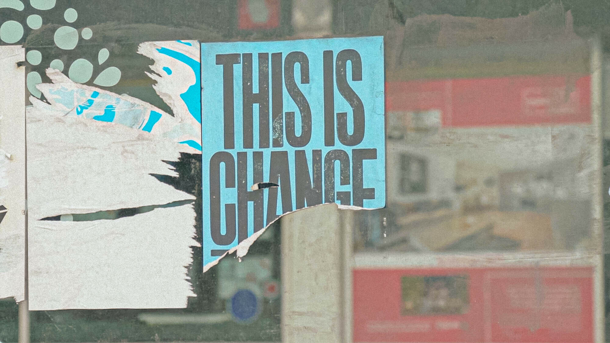 A torn sign in a shop window reads: 'THIS IS CHANGE' during lockdown